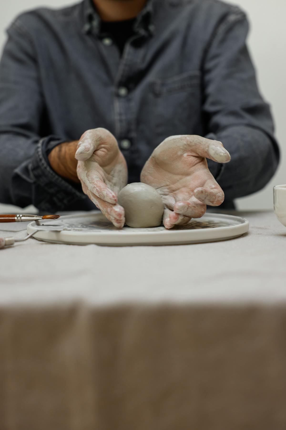 Ceramicist's hands shaping wet clay on the wheel